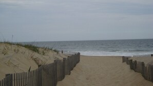 Een zandstrand met een houten omheining langs het water.