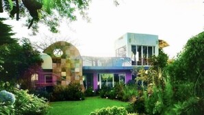 A modern house with a unique architectural design, featuring a curved structure and a mix of materials.