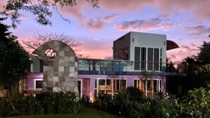 A modern house with a glass facade, a stone archway, and a well-maintained garden.