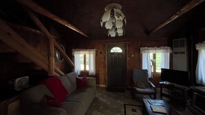 L’intérieur d’un chalet accueillant, avec un canapé, un fauteuil et une table sur laquelle sont posés des livres.