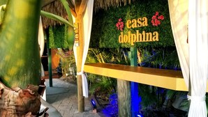 Un sentier mène à une construction au toit de chaume sur laquelle est apposée une enseigne indiquant « Casa Dolphina ».