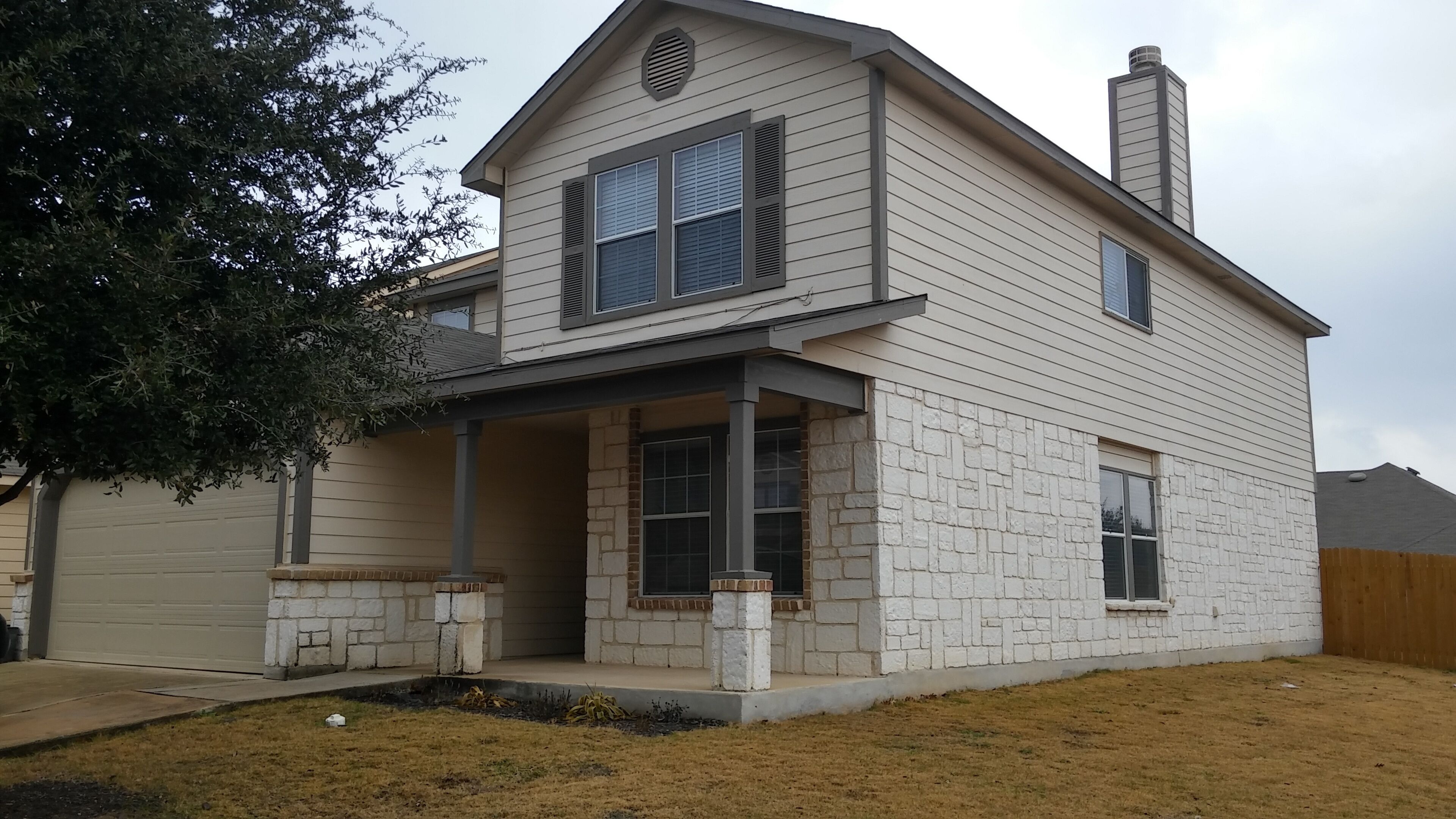 Une maison à deux étages, avec des fondations en pierre, un porche abrité et un garage.