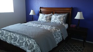 Un letto con copriletto e cuscini decorati, illuminato da due lampade sui comodini.