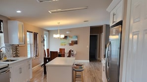 A modern kitchen with a central island, white cabinetry, and a stainless steel refrigerator. - Manatee Bay , Pool table, Pool, Kayaks, Jacuzzi not working.  (Marathon)