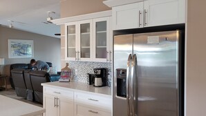 A modern kitchen with white cabinets, a stainless steel refrigerator, and a coffee maker on the counter. - Manatee Bay , Pool table, Pool, Kayaks, Jacuzzi not working.  (Marathon)