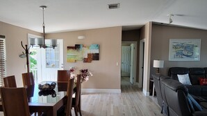 A spacious living area with a dining table and chairs, a black leather sofa, and a hallway leading to another room. - Manatee Bay , Pool table, Pool, Kayaks, Jacuzzi not working.  (Marathon)