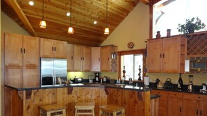 A kitchen with wooden cabinets, a stainless steel refrigerator, a sink, and a bar area with stools. - Tahoe Ski Lodge  WiFi, hot-tub sleeps 12 (Truckee)