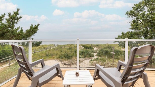 A balcony with two chairs and a table, overlooking a beach and dunes. - On Beach, Sunsets, Bikes+Kayaks, Pet Friendly, Firepit, Serenity.  (Villas)