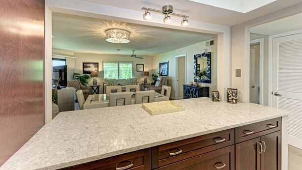 A spacious kitchen with a large island, dark wooden cabinets, and a modern chandelier. - Sea Grape Inn #5- Beachfront Property (Longboat Key)