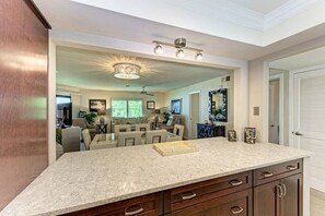 A spacious kitchen with a large island, dark wooden cabinets, and a modern chandelier. - Sea Grape Inn #5- Beachfront Property (Longboat Key)