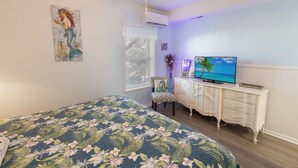 A bedroom with a bed, a dresser, a television, and a window with blinds. - #110 Picture Perfect Studio w Sleeper Sofa & Pool (Isle of Palms)