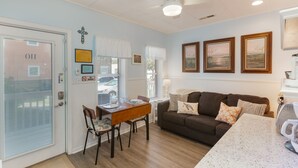 A cozy living room with a brown sofa, a dining table with chairs, and a kitchen area with a countertop. - #110 Picture Perfect Studio w Sleeper Sofa & Pool (Isle of Palms)