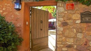 Een rustieke stenen muur met een houten poort en een bord waarop 'La Villa Rouge' staat.