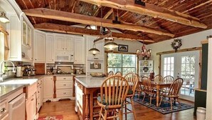 A spacious kitchen with wooden beams, white cabinetry, and a central island with chairs. - 16-Acre Resort Ranch with 4 Homes Included, Pool, Spa, Firepit &Gathering Spaces (Kyle)
