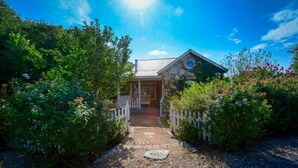 A house with a porch, surrounded by lush greenery and a clear blue sky. - 16-Acre Resort Ranch with 4 Homes Included, Pool, Spa, Firepit &Gathering Spaces (Kyle)