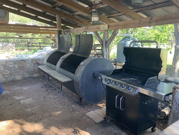 Zona de barbacoa con pared de piedra, un banco y un letrero que dice "KING OF THE GRILL".