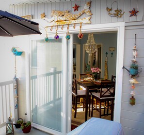 A dining area with a table set for two, a chandelier, and decorative wall hangings.