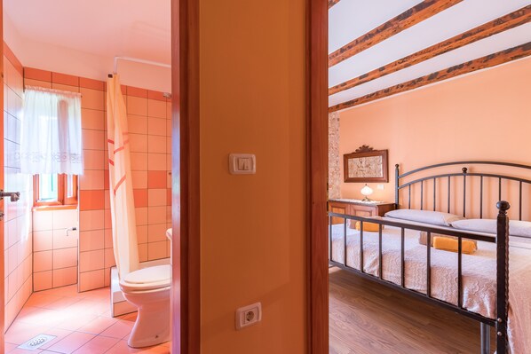 Een badkamer met toilet, douchegordijn en betegelde wanden.