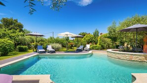 A swimming pool with lounge chairs and umbrellas, surrounded by greenery. - Authentic Istrian House - Apartment with saltwater pool- 15 min from Kamenjak (Pula)