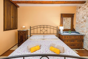 A bedroom with a bed, a dresser, a nightstand, a lamp, and a mirror.