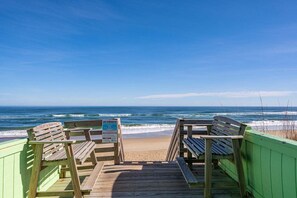 Une terrasse en bois avec des bancs donnant sur une plage.
