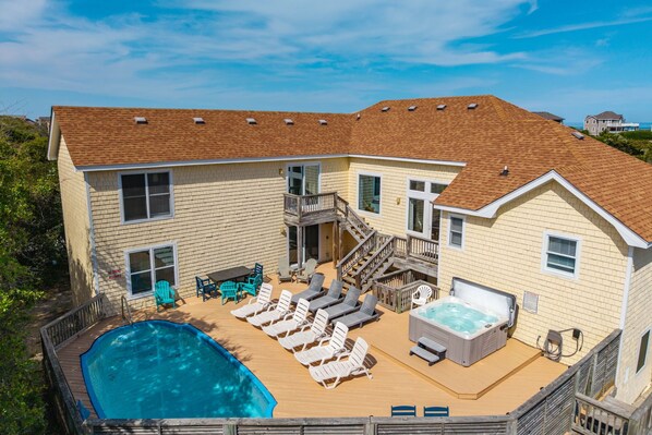 Une maison à deux étages dotée d’une piscine, d’un espace salon extérieur et d’un jacuzzi.