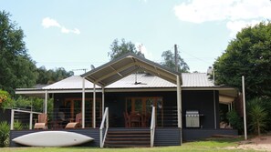Une maison avec une véranda couverte, un barbecue et une planche de surf.