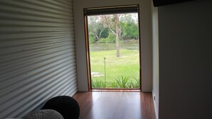 Una habitación con puerta de vidrio corrediza que da a un espacio exterior con césped, árboles y una masa de agua.