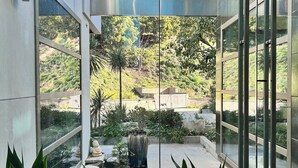 A modern building with large glass windows, a small water feature, and various plants. - Private Custom Modern 10,000 sq. Ft. Estate -- Nestled on 15 Acres (Temecula)