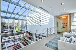 Experience the airy feel of this room with a high ceiling and large skylight, featuring a comfortable seating area and glass partition.