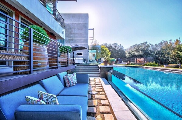 Relax by the pool in a serene outdoor space with a sofa, potted plants, and a seating area.