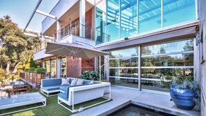 A modern outdoor living area with a pool, seating, and a glass facade. - Private Custom Modern 10,000 sq. Ft. Estate -- Nestled on 15 Acres (Temecula)