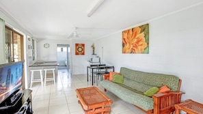 Ein Wohnzimmer mit Sofa, Couchtisch und Fernseher. Es gibt einen Essbereich mit Tisch und Stühlen.