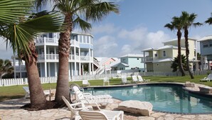 A pool area with lounge chairs and a stone patio. - Quiet, Big, Bright and Beautiful!  Perfect Beach House for Family and Friends (Port Aransas)
