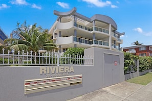 A modern multi-story building with balconies, a gated entrance, and a sign indicating it is a post office. - Riviera 203 - Prime CBD Location (Port Macquarie)