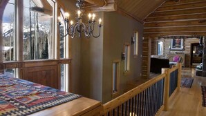 A wooden interior with a large window, a chandelier, and a wooden railing. - 5 BR + Loft Luxury Ski-in & Ski-out Log Home, stunning mountain views, hot tub (Mt Village)
