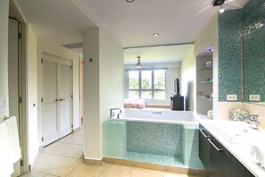 A modern bathroom with a large bathtub, a shower area, and a vanity with a mirror.