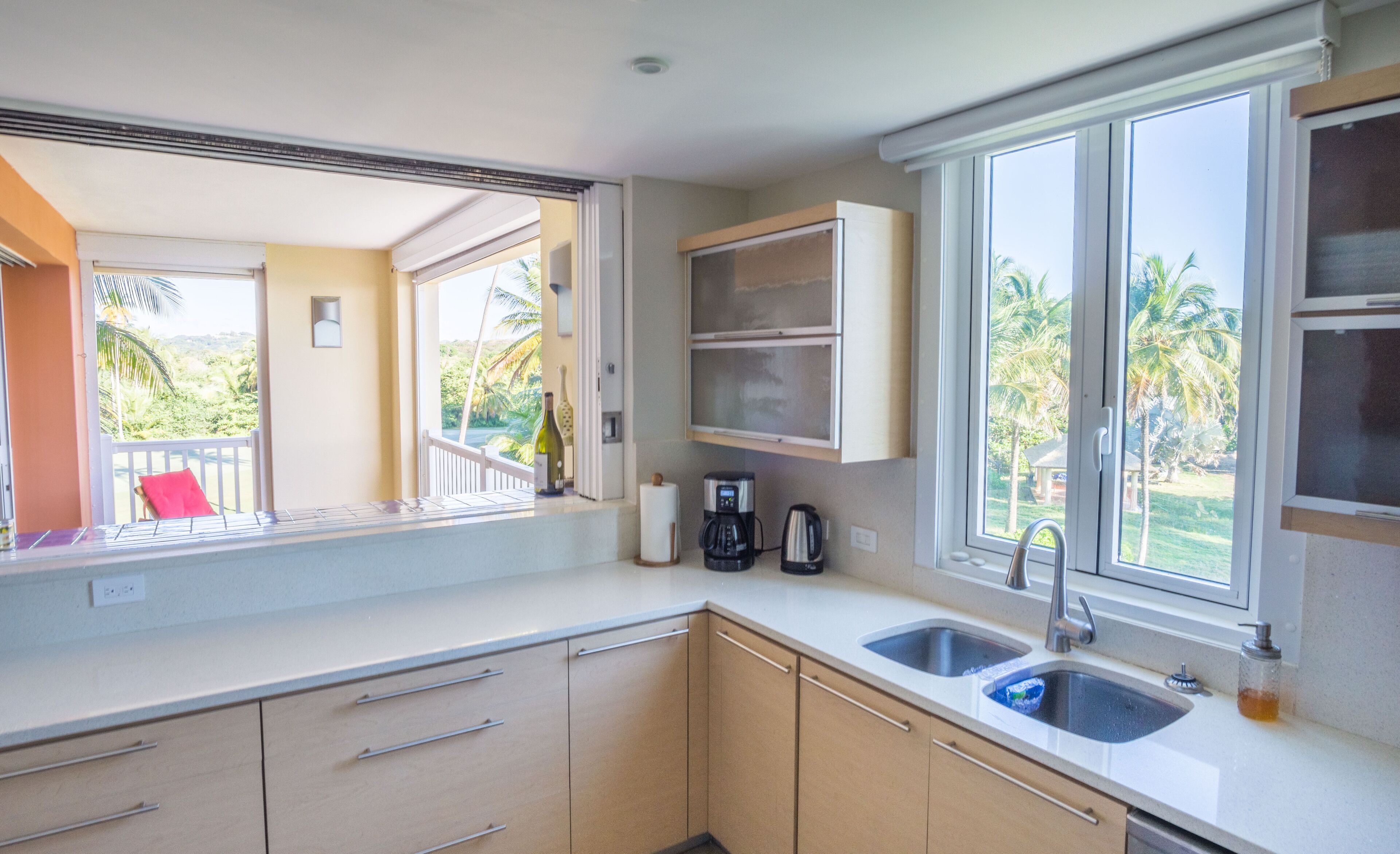 A kitchen with a large window, a coffee maker, and a sink.