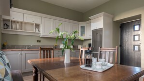 A kitchen with a wooden dining table, white cabinets, and a potted plant. - Castle View House, stunning period property. (Doolin)