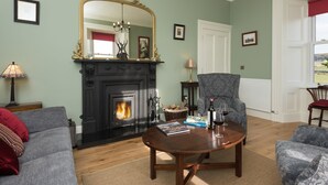 A living room with a fireplace, a large mirror, a sofa, and a coffee table. - Castle View House, stunning period property. (Doolin)