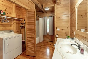A wooden cabin bathroom with a washing machine, a sink, and a mirror. - Log cabin in Amish country (Sugarcreek)