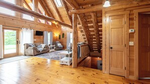 Ein großzügiger Wohnbereich mit Holzböden, einer Couch, einem Couchtisch und einer Treppe, die in eine andere Ebene führt.