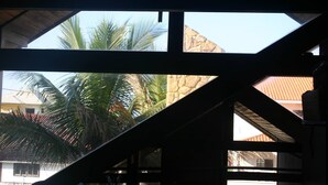 A room with a sloped ceiling, large windows, and a view of palm trees and a building outside.