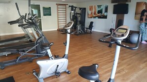 A gym with cardio machines, weight training equipment, and a wall with fitness posters. - Beachfront apartment in Praia do Futuro with full amenities. (Antonio Diogo)