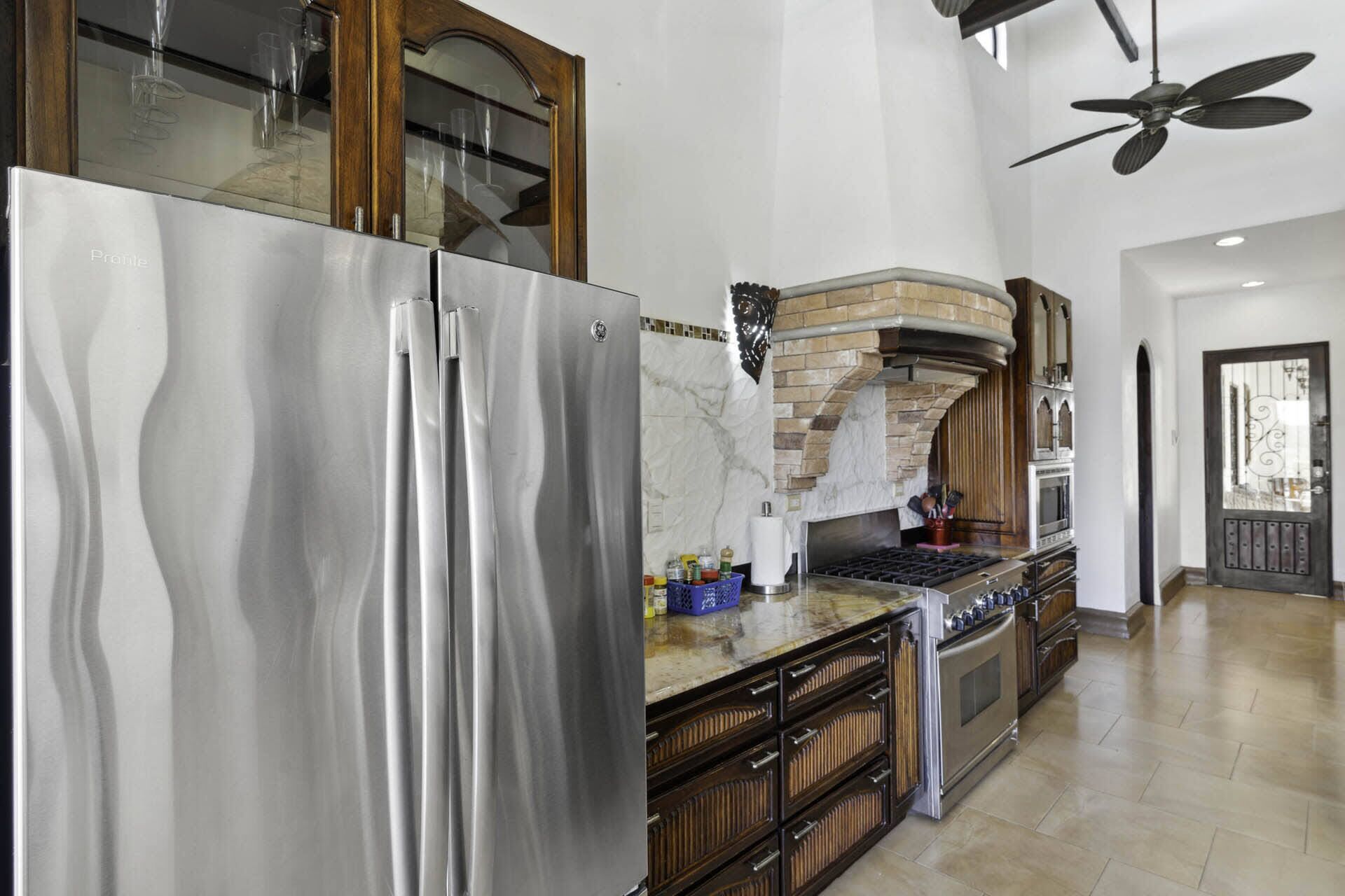 A modern kitchen with stainless steel appliances, a brick oven, and a large island with drawers.