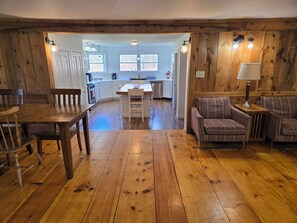 A wooden-floored living room with a dining table and chairs, a striped sofa, and a kitchen in the background. - Abigail's Country House. 2 minutes To Skiing. Swimming, Hiking very close by. (Hunter)