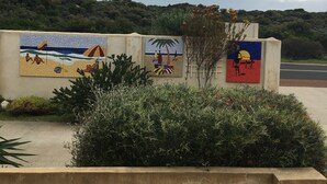 Un bâtiment orné d’une fresque représentant une scène de plage et un palmier.