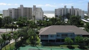 Un hotel frente al mar con varios pisos, rodeado de palmeras y vistas al océano.