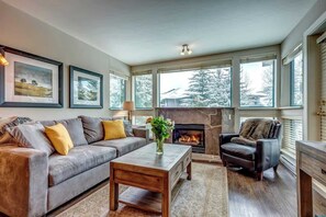 A living room with a fireplace, a sofa, a coffee table, and a chair. - Greystone Lodge 221 Ski-in/Out by Acer Vacations (Whistler)