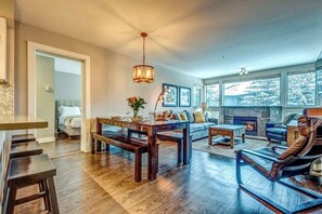 A spacious living room with a wooden dining table, a sofa, a recliner, and a fireplace.